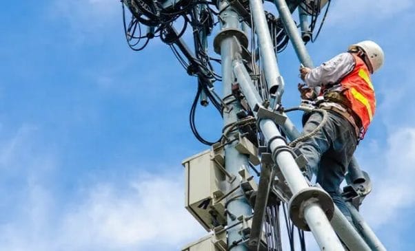 electronics engineer climbing a telecom antenna pole