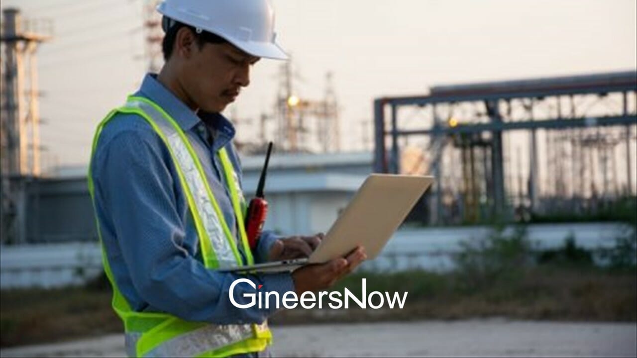 construction civil engineer holding a tech laptop at project site with PPE, safety vest, radio, hard hat